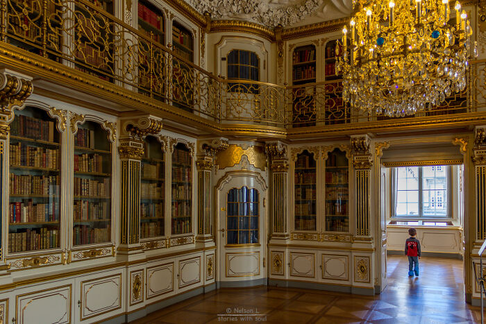 Grandiose library interior with ornate gold details, tall bookshelves, and a child exploring a magical bookstore setting. Grandiose library interior with ornate gold details, tall bookshelves, and a child exploring a magical bookstore setting.