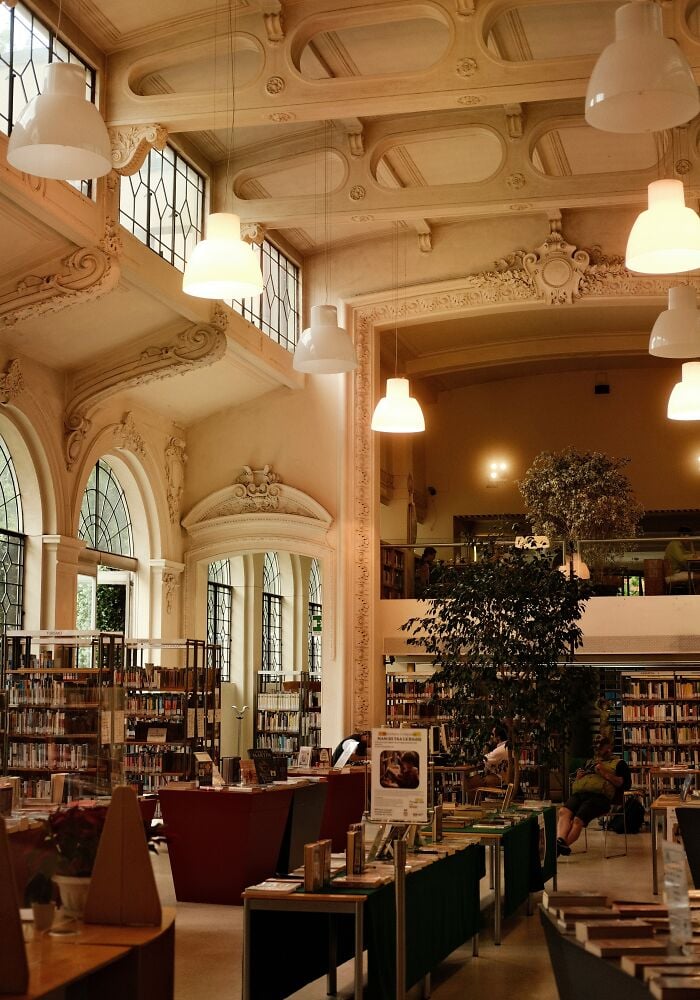 Interior grandioso de biblioteca com tetos altos, arquitetura ornamentada, grandes janelas, estantes de livros e áreas de leitura aconchegantes. Interior grandioso de biblioteca com tetos altos, arquitetura ornamentada, grandes janelas, estantes de livros e áreas de leitura aconchegantes.