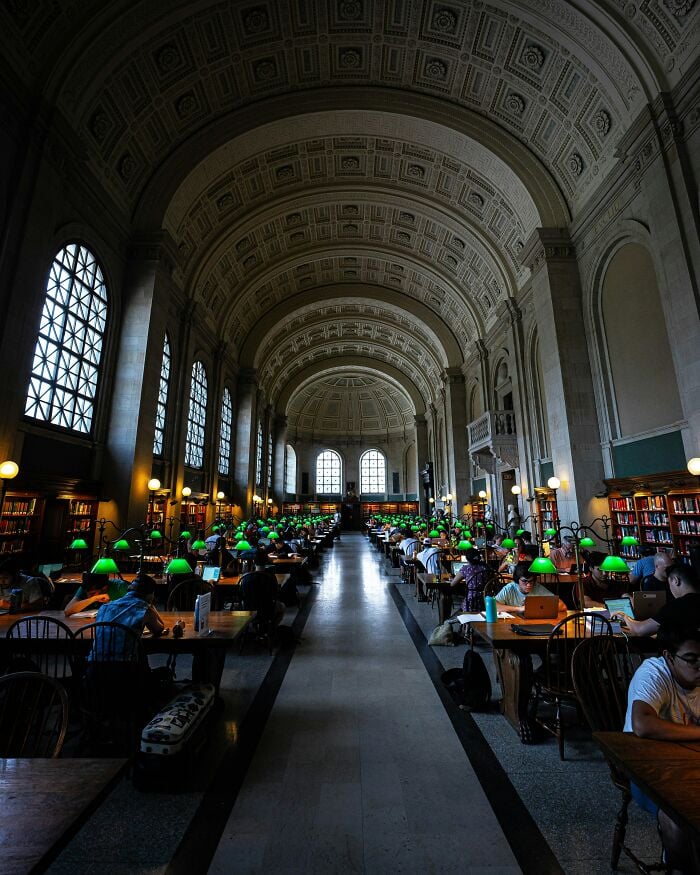 Interni grandiosi della biblioteca con alti soffitti a volta, grandi finestre e file di tavoli da studio con lampade verdi e lettori. Interni grandiosi della biblioteca con alti soffitti a volta, grandi finestre e file di tavoli da studio con lampade verdi e lettori.