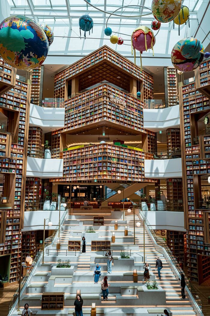 Interni grandiosi della biblioteca con imponenti librerie, grande lucernario e sculture di pianeti colorati appese al soffitto. Interni grandiosi della biblioteca con imponenti librerie, grande lucernario e sculture di pianeti colorati appese al soffitto.